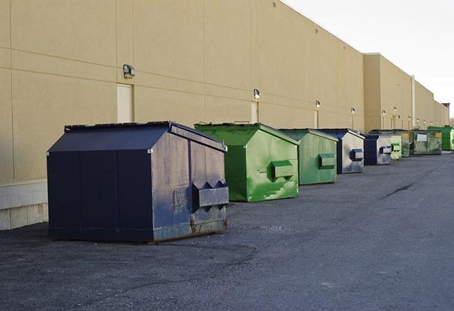 a construction worker unloading debris into a blue dumpster in Brainerd